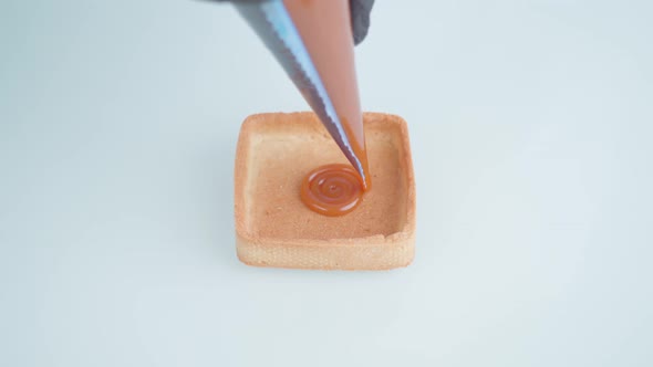 Person Fills Biscuit with Caramel Drawing with Piping Bag