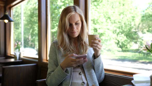 woman with smartphone drinks coffee in a tram cafe