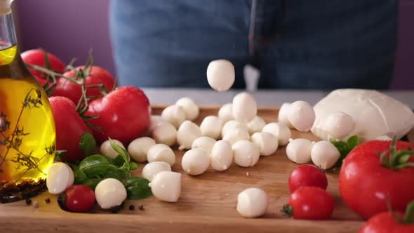 Mozzarella Cheese Small Balls Falling on Wooden Cutting Board