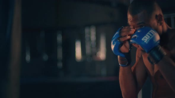 Male Fighter Works Out in the Dark Gym