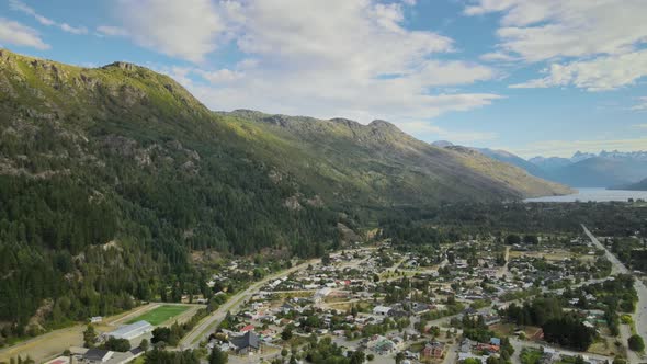 Pan right flying Lago Puelo valley between Andean mountains covered in pine tree woods with lake in