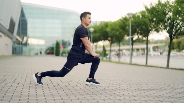 young active asian fit man engaged in physical exercise stretching outdoor street.