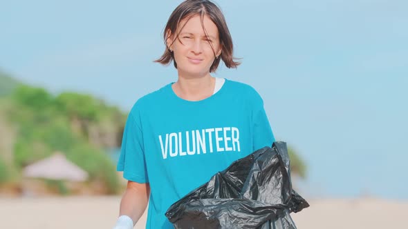 Young Caring Woman Volunteer Posing Throwing Plastic Bottle in Black Bag
