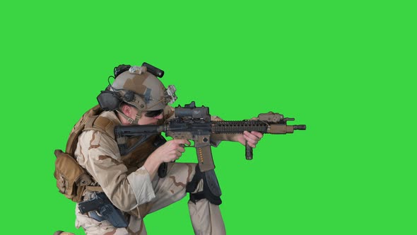 Paratrooper in Uniform Shooting From Sitting Position on a Green Screen, Chroma Key.