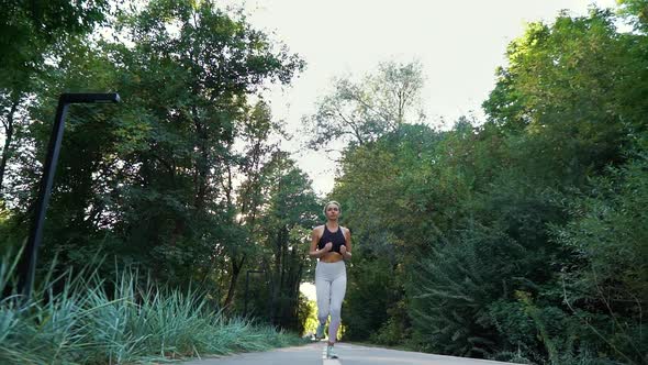 Fit Blonde Woman Jogging in Summer Park