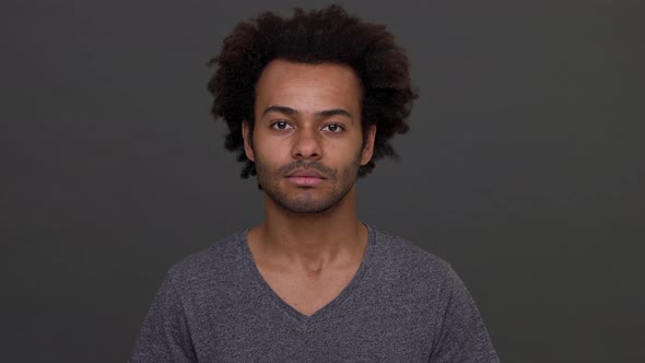 Young Darkskinned Male with Afro Haircut Cheerfully Nodding Isolated Over Charcoal Background