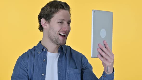 Online Video Chat on Tablet By Young Man on Yellow Background