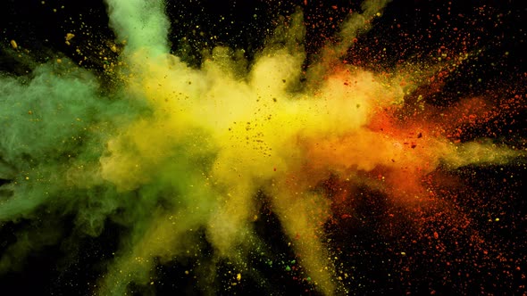 Colorful powder/particles fly after being exploded against black background. Slow Motion.