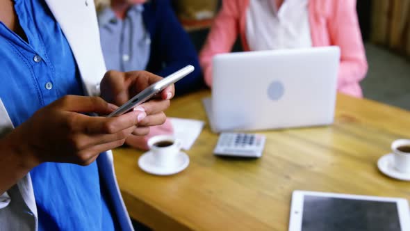 Woman text messaging on mobile phone in cafeteria