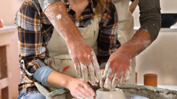 Male potter assisting female potter