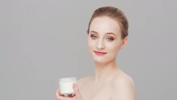 Studio portrait of young, beautiful and natural woman over grey background.