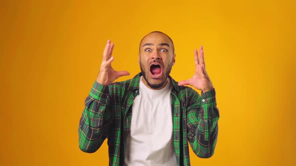 Very Scared Shocked Man Screaming and Putting Hands Up Against Yellow Background