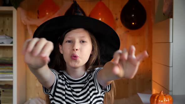 Little Pretty Girl Witch in Black Wizard Hat Says Boo with Scary Gesture