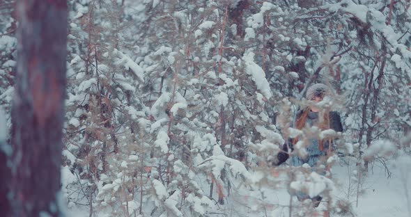 Girl Walks Through the Winter Forest and Touches the Branches of Trees