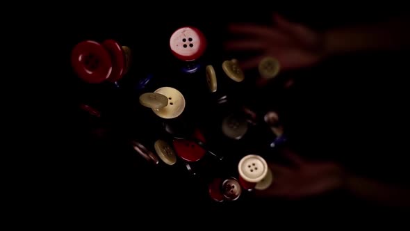 Person Throws Up Coloured Buttons of Various Size Macro