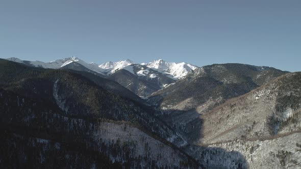 Aerial Landscape Mountains Covered with Forest and Snowcapped Peaks in the Background