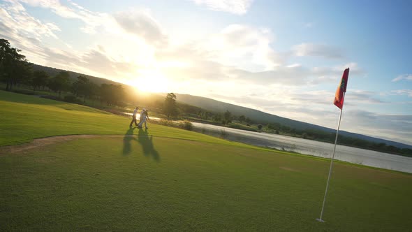 4K Group of Asian man golfer walking on golf course with talking together at summer sunset