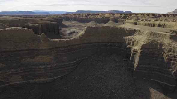 Flying low over desert cliffs towards open valley in the desert