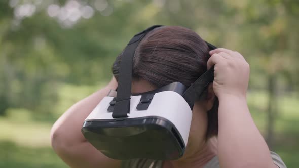 Closeup Young Woman with Dwarfism Putting on VR Headset in Slow Motion Standing in Spring Summer