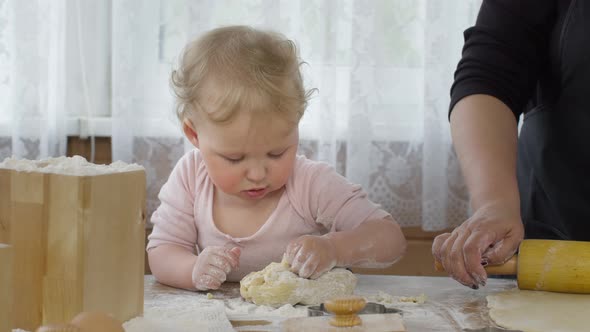 Cute Baby Granddaughter Mixes Dough for Pastry with in Kitchen and Funny Smile