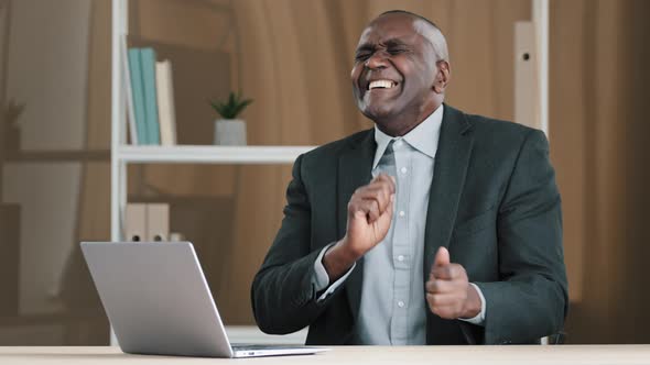 African Old 50s Happy Silly Businessman Funny Joyful Carefree Boss Middleaged Man Sitting Desk in