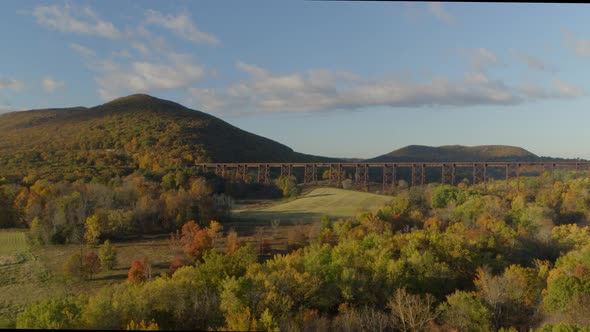 Wide shot of railroad bridge passing over valley landscape between mountains