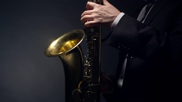 Man plays the saxophone with hands in profile. Wind sax musical instrument on black background.