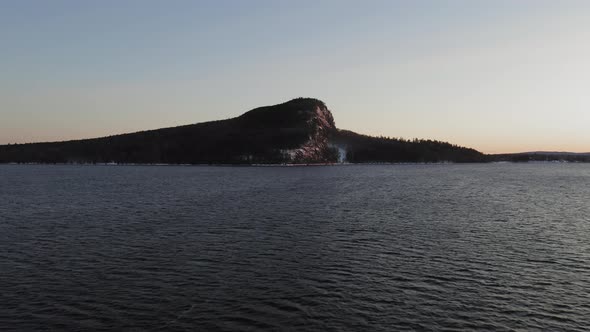 Slowly flying towards a lone mountain across a lake at dawn AERIAL