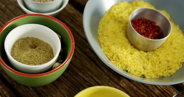 Yellow rice with various spice on wooden table 4k