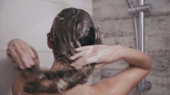 Back Look of Woman Washes Head Under Shower