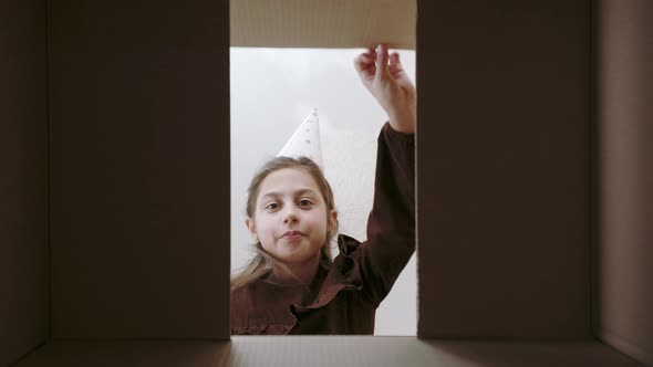 Excited Female Child in Party Hat Unpacking Birthday Gift