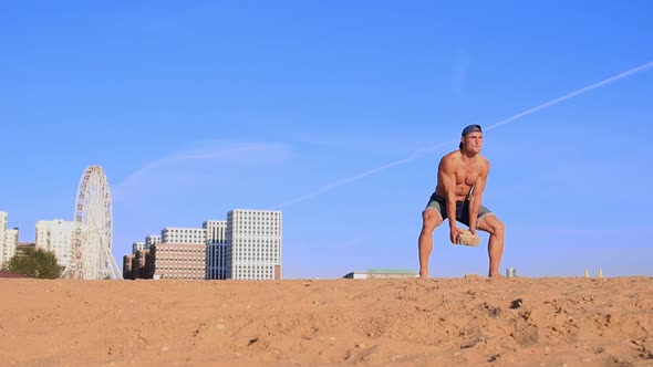 Young Fit Man Doing Sports Exercises at the Beach  Raising Heavy Rock in His Hands