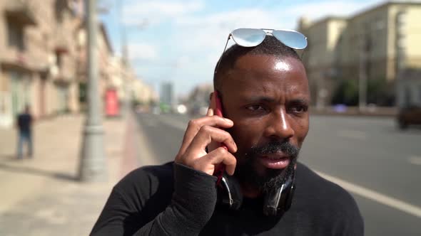 Close-up of an African-American Man Arguing on a Smartphone in a Modern City Against the Background