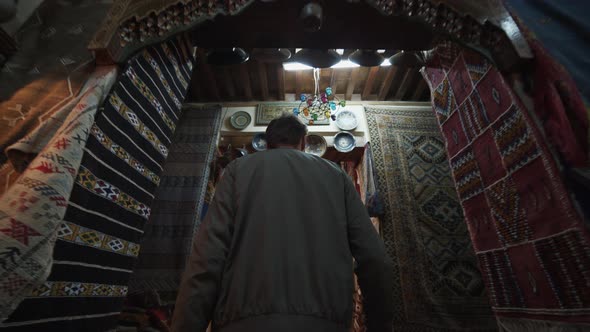 SLOW MOTION: YOUNG CURIOUS MAN WALKING INTO OLD FABRIC STORE WITH COLORFUL CARPETS IN OLD TOWN OF