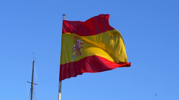 The Spanish flag blowing in the wind, blue sky background SLOMO.