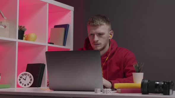 Designer in Red Sweatshirt Works at Computer From Home. Workspace Red Backlight