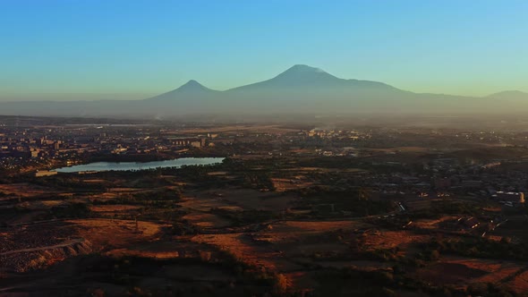 Aerial Drone Shot Tilt Up Fly Over Fields and Houses and Mount Aragats in Twilight