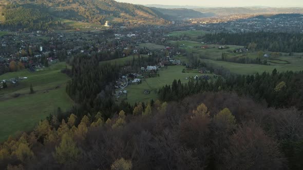 Aerial above forest with view of Zakopane village in Poland, dawn