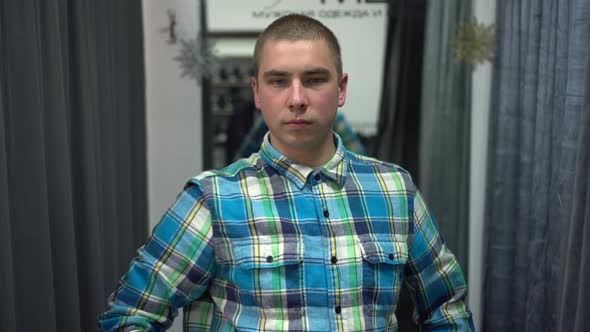 A Young Man Opens the Curtain in the Fitting Room. Clothing Store.