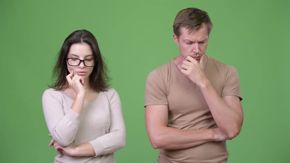 Young Sad Couple Thinking Together Against Green Background