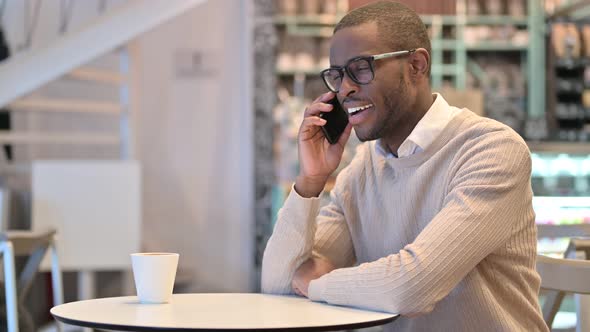 Attractive African Man Talking on Smartphone in Cafe 