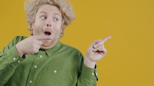 Portrait of Young Man Pointing Sidewards and Smiling with Thumbsup Hand Gesture on Yellow Background