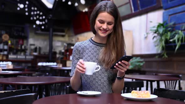 Beautiful Woman Using Phone In Cafe, Drinking Coffee