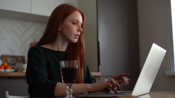 Attractive Busy Young Woman Drinking Wine From Glass While Working Typing on Laptop Computer Sitting