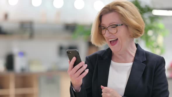 Portrait of Excited Old Businesswoman Celebrating Success on Smartphone 