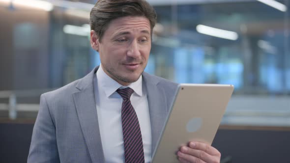 Portrait of Video Call on Tablet by Middle Aged Businessman