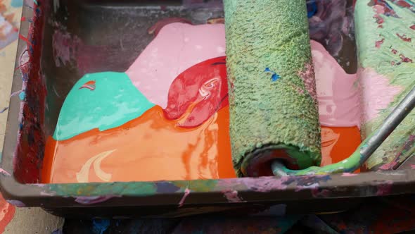 Paints with a roller. Close-up of a paint roller in bright colors in a paint tray. Painting works