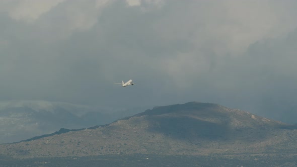 Aircraft Gaining Height and Flying Over Mountains in Cloudy Sky