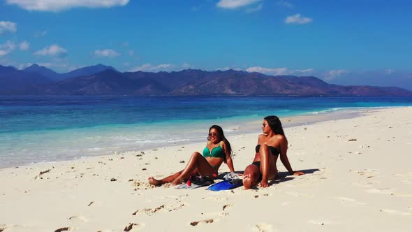 Ladies enjoying life on beautiful coast beach break by shallow ocean and white sandy background of L