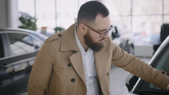 A Respectable Adult Man Chooses a Car in the Auto Show of an Official Dealer